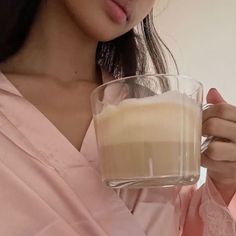 a woman is holding a glass with some liquid in it