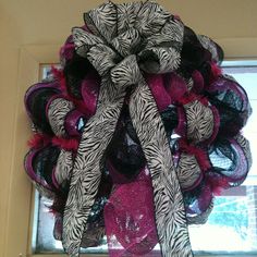 a purple and black wreath hanging from the front door with zebra print ribbon on it