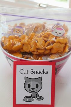 a bowl filled with cat snacks sitting on top of a table next to a sign