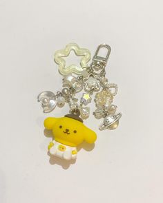 a key chain with charms attached to it on a white surface, featuring a yellow dog