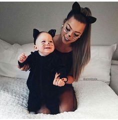 a woman holding a baby wearing cat ears