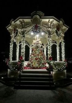 a lit up christmas tree in front of a gazebo