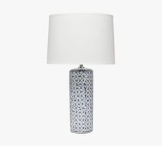 a blue and white vase lamp with a white shade on it's side, against a white background