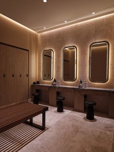 a bathroom with three sinks, mirrors and two stools in it's center