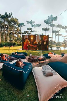 two people laying on bean bags in front of a movie screen with palm trees behind them