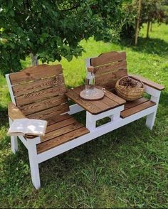 two wooden benches sitting on top of a grass covered field next to a basket filled with fruit