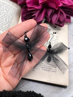 a person is holding two black bows in their hand next to an open book and flowers