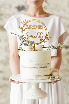 a woman holding a cake with the words mr and mrs on it in gold lettering