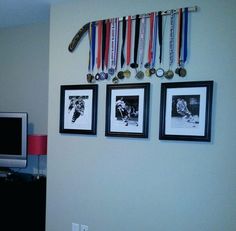 three framed pictures hang on the wall above a flat screen tv with medals hanging from it