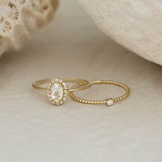 two gold rings sitting on top of each other next to a white rock and coral