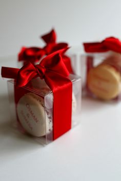 two small clear boxes with red bows and macaroons in them, both wrapped in plastic