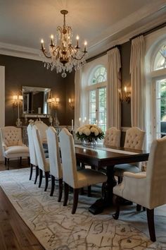 a formal dining room with chandelier and large table surrounded by white upholstered chairs