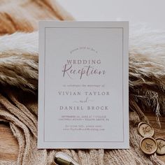 the wedding reception card is laying on top of a fur - lined blanket with two gold buttons