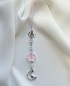 a pink and white beaded keychain with a crescent charm hanging from it's side