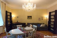 a living room filled with furniture and a chandelier hanging from the ceiling over a table