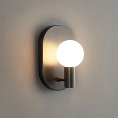 a light that is on the wall next to a white wall mounted lamp with a round glass shade