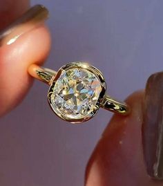 a close up of a person's hand holding a ring with a diamond in it