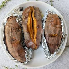 three baked potatoes sitting on top of tin foil