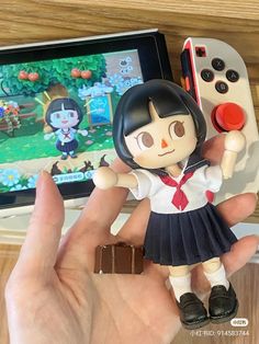 a person holding a toy next to a nintendo wii game controller on a wooden table