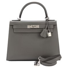 Hermes brand new Kelly 28 in Gris Mouette epsom leather with brushed palladium hardware and tonal stitching. It comes with a two strap with front toggle closure, clochette with lock and two keys, single rolled handle and removable shoulder strap. The interior has one zip pocket with Hermes engraved pull and two open pockets on the opposite side. Kelly Hermes, Hermes Clothes, Hermes Kelly Bag, Grey Bag, Kelly Bag, Birkin 25, Hermes Bags, Hermes Bag, Birkin Bag