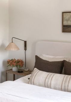 a bedroom with a bed, lamp and pictures on the wall above it's headboard