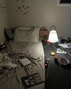 an unmade bed in a messy room with many things on the floor around it