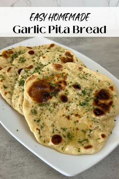 three flat breads on a white plate sitting on a marble counter top, with herbs sprinkled all over them