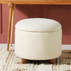 a white ottoman sitting on top of a rug next to a wooden table and chair