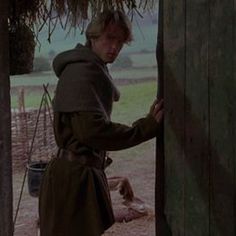 a man in an old - fashioned outfit is leaning on a door and looking at something