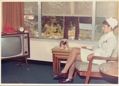 a woman sitting in a chair next to a dog on a table and a tv