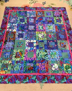 a multicolored patchwork quilt is laying on top of a rug with flowers and leaves