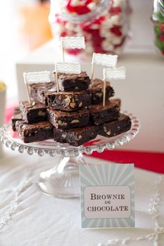 brownies are stacked on top of each other on a cake plate with small flags sticking out of them