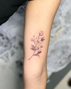 a woman's arm with a small flower tattoo on the left side of her arm