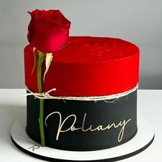 a red rose sitting on top of a black and white cake with writing on it