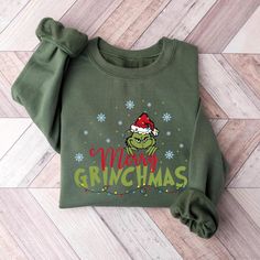 a green sweatshirt with the words grinmas on it and a red santa's hat