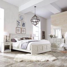 a large white bed sitting in a bedroom on top of a hard wood floor next to a window