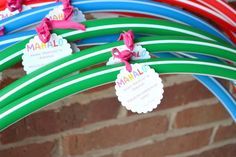 there are many different colored hoses hanging from the brick wall with name tags on them