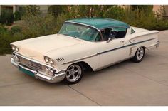 an old white and green car parked in a driveway