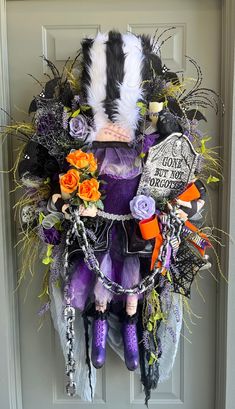 a wreath decorated with purple and black items is hanging on the front door for halloween