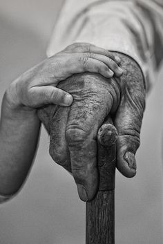 the hands of two people holding on to a cross