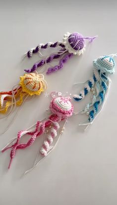 three crocheted jellyfishs are shown in different colors and sizes on a white surface