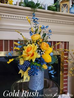 a vase filled with yellow and blue flowers sitting on top of a table next to a fireplace