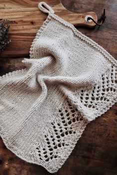 a knitted dishcloth on top of a wooden table next to a pair of scissors