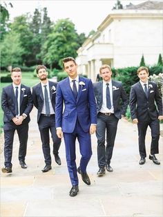 a group of men in suits and ties walking down a sidewalk with trees behind them