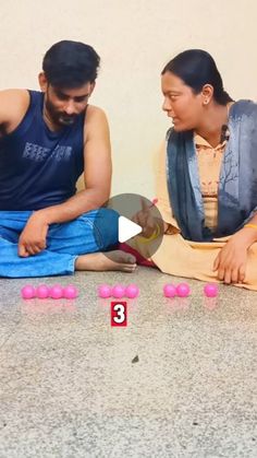 two people sitting on the floor with pink balls in front of them