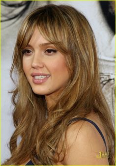 a woman with long hair and bangs smiling at the camera