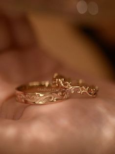 two gold wedding rings sitting on someone's hand