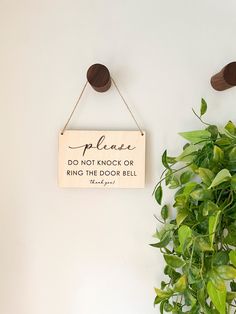 a wooden sign hanging from the side of a wall next to a potted plant