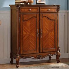 a wooden cabinet with two doors and some pictures on it's top, in front of a blue wall