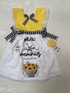 a yellow and white dress with sunflowers on the front, saying meal memories made here